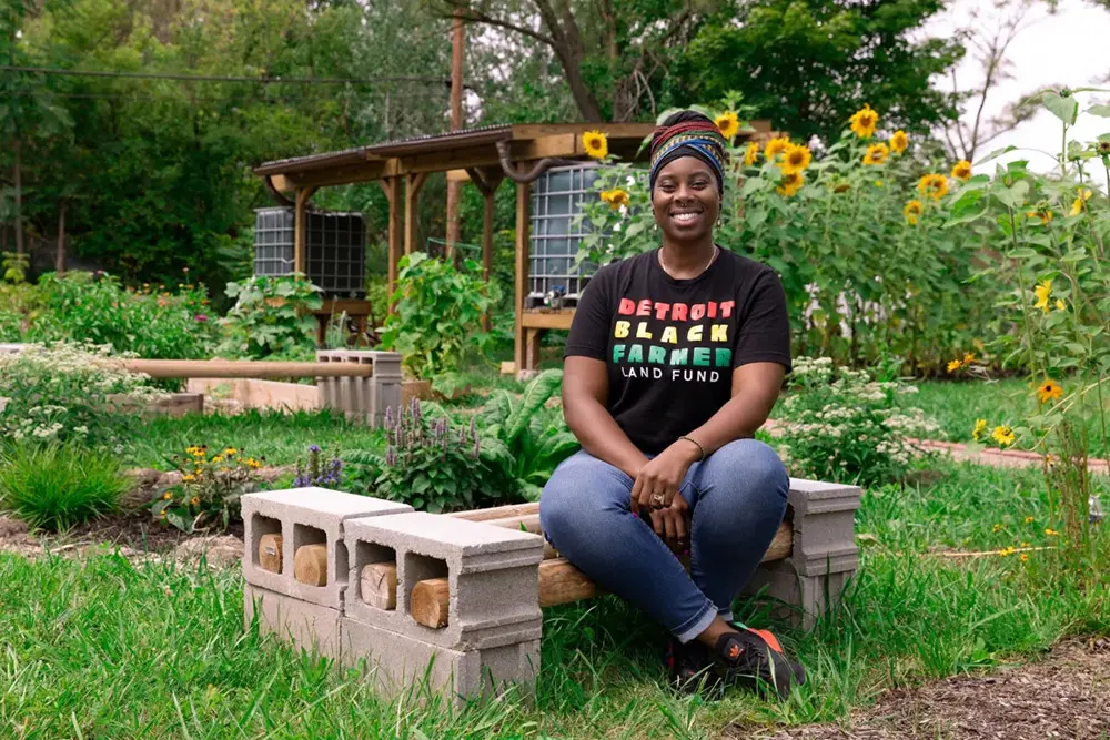 Detroit Black Farmer Land Fund member sitting in a garden with sunflowers