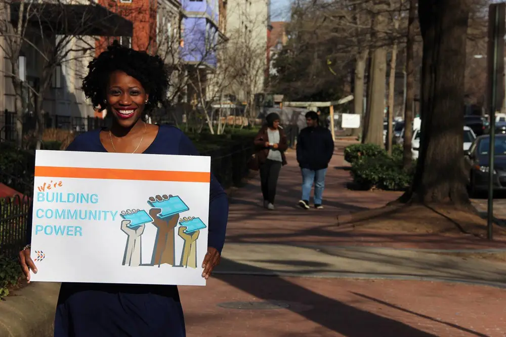 Groundswell member holding a sign that read We're building community power.