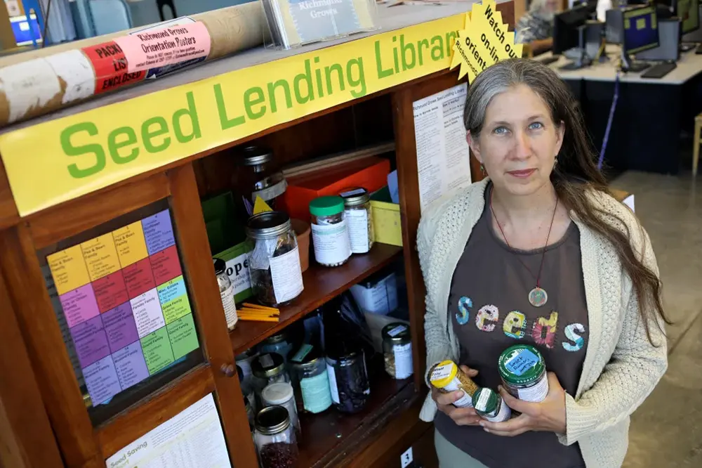 Woman standing in front of a seed lending library shelf
